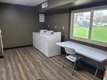 A room with a white table and chairs, a window, and a white cabinet.